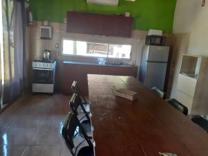 a kitchen with a long wooden table and a refrigerator at Complejo La posta del Hum in Paso de los Toros