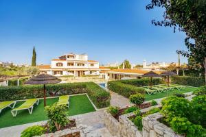 a house with a garden with chairs and umbrellas at Muthu Balaia Sol in Albufeira