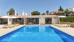 a swimming pool with chairs and a house at Muthu Balaia Sol in Albufeira