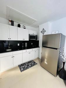 a kitchen with a stainless steel refrigerator and white cabinets at Cozy Suite in St Petersburg