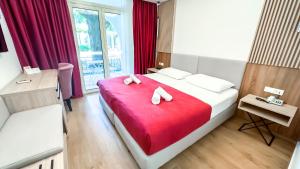 a hotel room with a bed with a red blanket at Hotel Slovenska Plaza in Budva