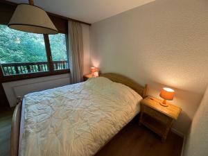 a bedroom with a bed and a window and two lamps at Mandarin B10 in Crans-Montana