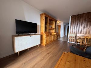 a living room with a flat screen tv on a cabinet at Mandarin B10 in Crans-Montana