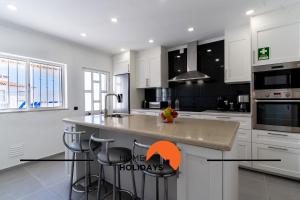 a kitchen with white cabinets and a island with bar stools at #248 Villa Loureira 54 by Home Holidays in Albufeira