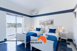two beds in a bedroom with an orange sign that says home holidays at #248 Villa Loureira 54 by Home Holidays in Albufeira