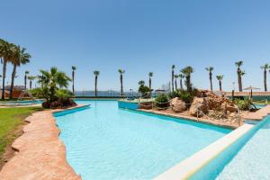 a swimming pool at a resort with palm trees at Primera linea de playa in La Manga del Mar Menor