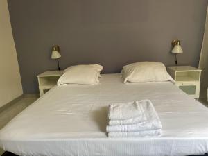 a white bed with two pillows and towels on it at Petite Maison avec Terrasse in Roquebrune-Cap-Martin