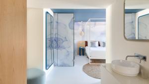 a white bathroom with a sink and a bed at Hotel Indigo Albufeira by IHG in Albufeira