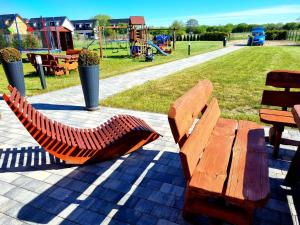 two wooden benches in a park with a playground at PRZYSTAŃ CISZY in Jantar