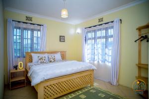 a bedroom with a large bed and two windows at Oasis Homestay in Arusha