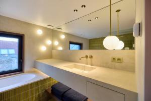 a bathroom with a sink and a tub and a mirror at Huis Langestraat 52 in Nieuwpoort +12 photos