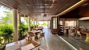 a restaurant with wooden tables and chairs and windows at Deva Beach Resort Samui in Choeng Mon Beach