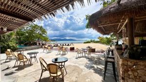 a patio with tables and chairs on the beach at Deva Beach Resort Samui in Choeng Mon Beach
