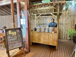 a man standing behind a counter with plates at Deva Beach Resort Samui in Choeng Mon Beach +37 photos