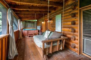 un porche d'une cabane en rondins avec un lit dans l'établissement Nice View Fireplace, Hot Tub, Porch Bed, Private, à Sevierville