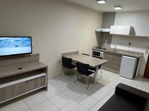 a kitchen with a table and chairs and a television at Apartamentos Riviera Park in Caldas Novas