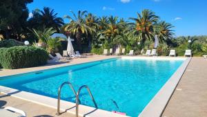 a swimming pool in a resort with palm trees at Agriturismo Baglio Vecchio in Castelvetrano Selinunte