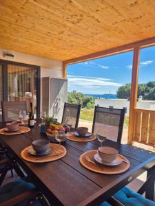 a wooden table with plates of food and wine glasses at Sea View Holidays - Mobilehome Pakostane in Pakoštane