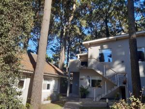 a white house with trees in the background at Cabañas Antares in Mar de las Pampas