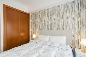 Un dormitorio con una cama blanca y una pared de madera. en Daimuz Holidays, en Daimuz