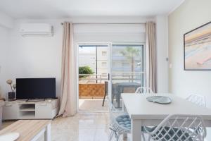 Sala de estar blanca con mesa y TV en Daimuz Holidays, en Daimuz