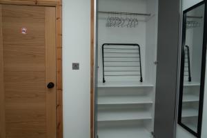 4 Bed Home, with 3 Bathrooms and Free Parking Home for Contractors & Workers- HOLIDAY PROMO FOR CHRISTMAS AND NEW YEAR في مانشستر: خزانة ملابس مع باب زجاجي ورفوف