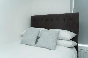 4 Bed Home, with 3 Bathrooms and Free Parking Home for Contractors & Workers- HOLIDAY PROMO FOR CHRISTMAS AND NEW YEAR في مانشستر: سرير مع وسائد بيضاء و اللوح الأمامي الأسود