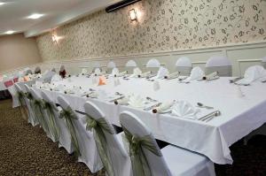 a long table with white tables and chairs in a room at Seacote Hotel in St Bees