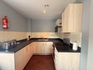 Una cocina con gabinetes de madera y un fregadero. en Newcastle Quayside Apartment -Sleeps 4 - Parking, en Newcastle