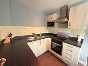 una cocina con armarios de madera y fregadero. en Newcastle Quayside Apartment -Sleeps 4 - Parking, en Newcastle