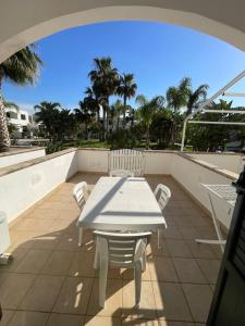 a white table and chairs on a balcony with palm trees at Le Palme House in Isola delle Femmine