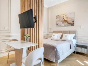 a bedroom with a bed and a table and a tv at WSCHODNIA ELEGANS Aparthotel in Łódź +96 photos