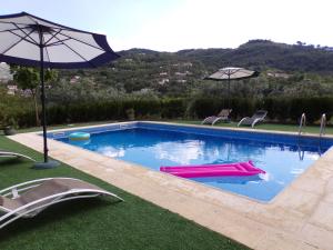 uma piscina com dois guarda-sóis e cadeiras em Casa do Passarinho em Resende