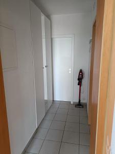 a hallway with a room with white walls and a vacuum at Apartment an der Fehnroute in Leer +5 photos