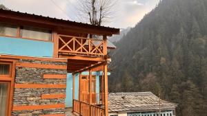 a building with a balcony in front of a mountain at The mysteryworld a-wooden tree cottage jibhi in Banjār