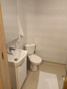 a white bathroom with a toilet and a sink at Sienkiewicza Centrum in Kielce