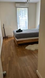 a bedroom with a bed with a wooden floor and a window at Appartement Cosy in Fresnes