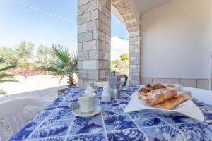 einen Tisch mit einem blauen und weißen Tischtuch mit Gebäck darauf in der Unterkunft Villetta Marika - Salento Reservation in Marina di Mancaversa