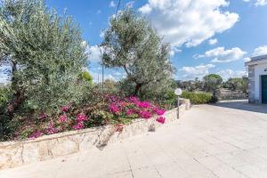 einen Garten mit rosa Blumen und Bäumen auf einem Gehweg in der Unterkunft Villetta Marika - Salento Reservation in Marina di Mancaversa