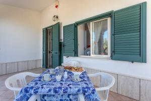 ein Tisch mit weißen Stühlen und einer blau-weißen Tischdecke in der Unterkunft Villetta Marika - Salento Reservation in Marina di Mancaversa + 43 Fotos