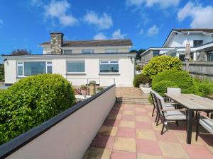 een huis met een patio en een tafel en stoelen bij Karenza in Penzance