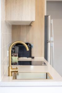 a kitchen sink with a gold faucet in a kitchen at Coastal Escape Watch Horses Pass Walk to Beach in Redcliffe +12 photos