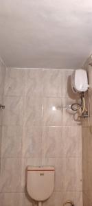 a bathroom with a toilet and a white tank at Hotel Krishna Palace in Dehu Road