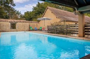 a blue swimming pool with chairs and an umbrella at L'Aile Est in Mayac +9 photos
