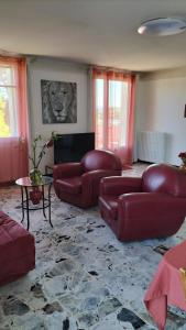 a living room with red leather couches and a table at Escale vélo La petite Reine in Cavaillon +8 photos