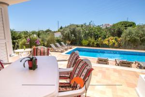 Un patio con mesa y sillas y una piscina. en #297 Moderna V3 com Piscina by Home Holidays, en Albufeira