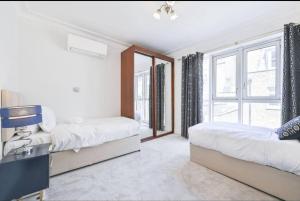 een slaapkamer met twee bedden en een raam bij CARLTON COURT - MAYFAIR in Londen
