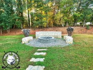 eine Feuerstelle in der Mitte eines Gartens in der Unterkunft WHITE WOLF Farmhouse Retreat in Reidsville