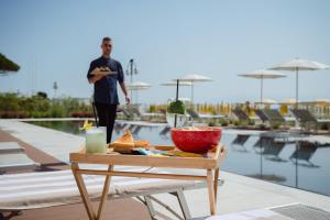 a man holding a plate of food on a table next to a pool at Hotel Las Vegas in Lido di Jesolo