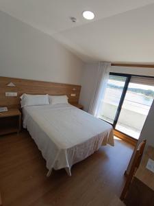 sypialnia z dużym łóżkiem i dużym oknem w obiekcie Hotel Brisa del Mar w mieście O Grove